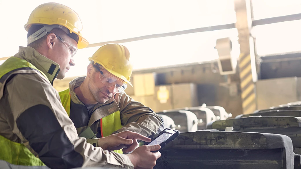 两位穿着正装的生意伙伴在仓库里查看一台平板电脑
