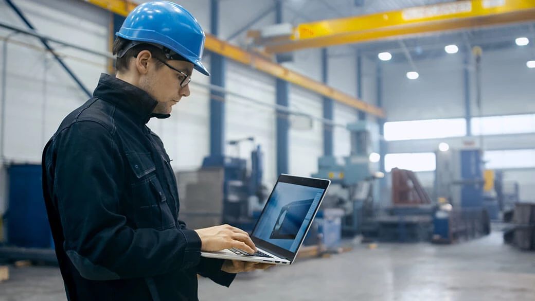 Factory worker using laptop with software